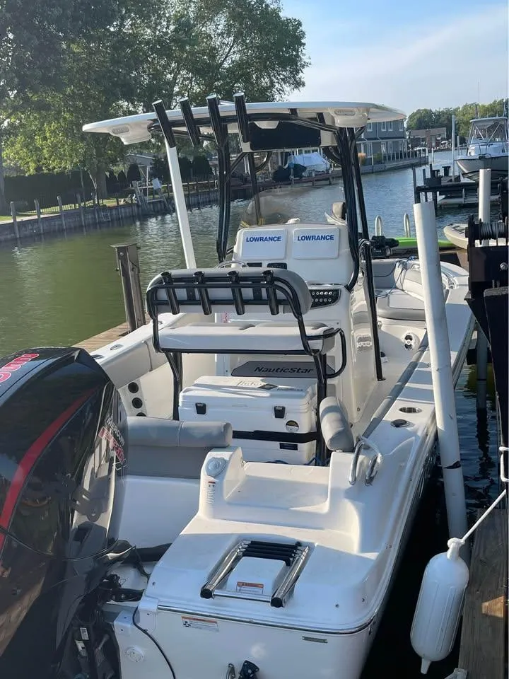 Slide: The Image of 2022 NauticStar 2302 Legacy boat docked by a serene waterfront. - 9