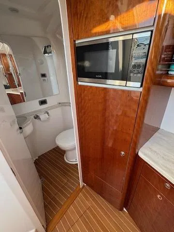 Slide: The Image of 2016 Intrepid 475 Panacea interior with wood finish, featuring a compact bathroom and microwave. - 39