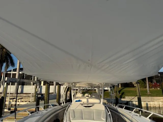 Slide: The Image of 2016 Intrepid 475 Panacea boat with spacious deck and canopy, docked near palm trees. - 44