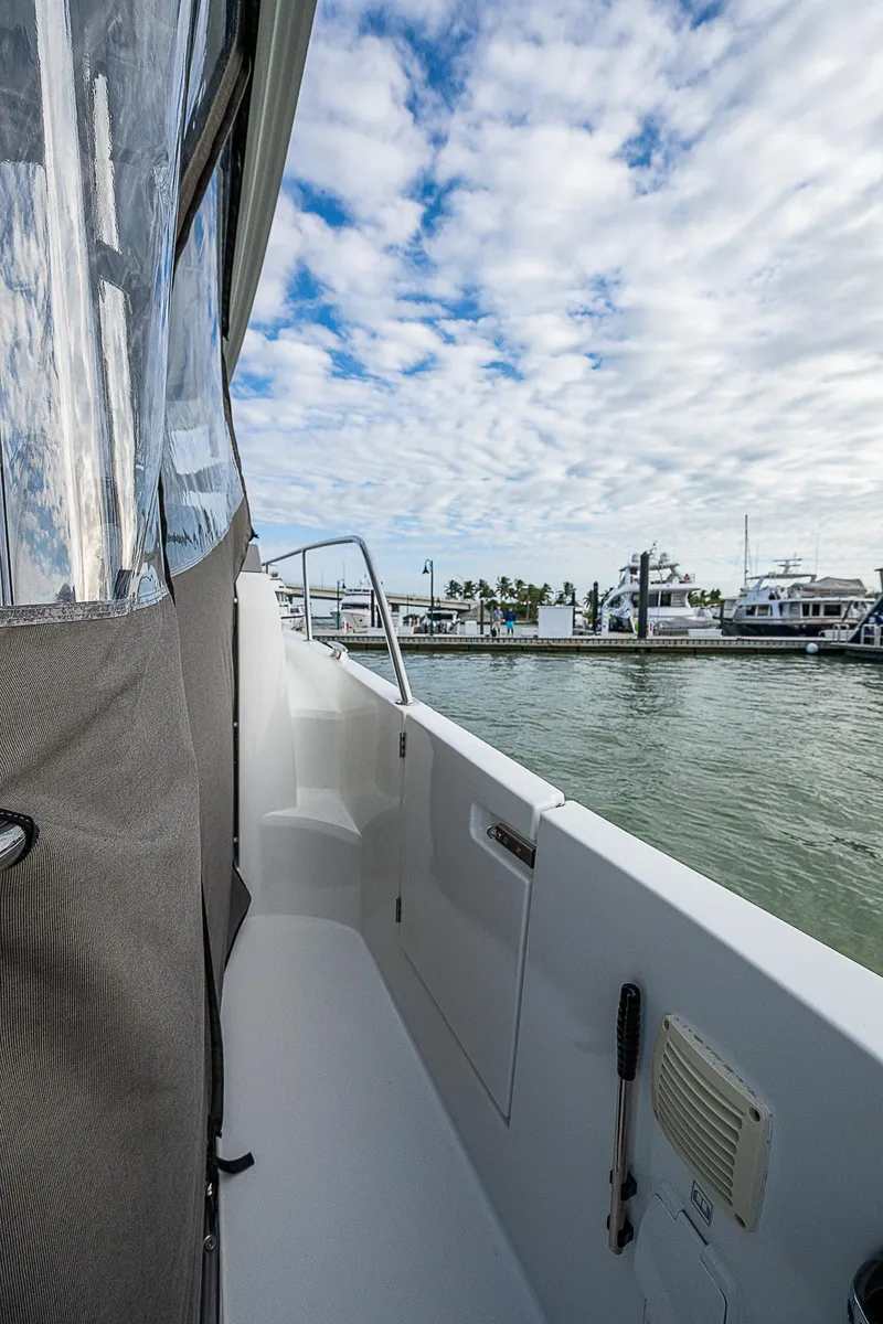 Slide: The Image of 2022 Jeanneau Leader 12.5 boat docked, side view with cloudy sky and marina background. - 27