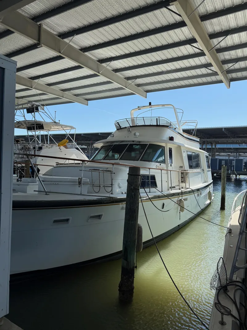 Slide: The Image of 1980 Hatteras 58MY yacht docked in a marina under a covered structure. - 1