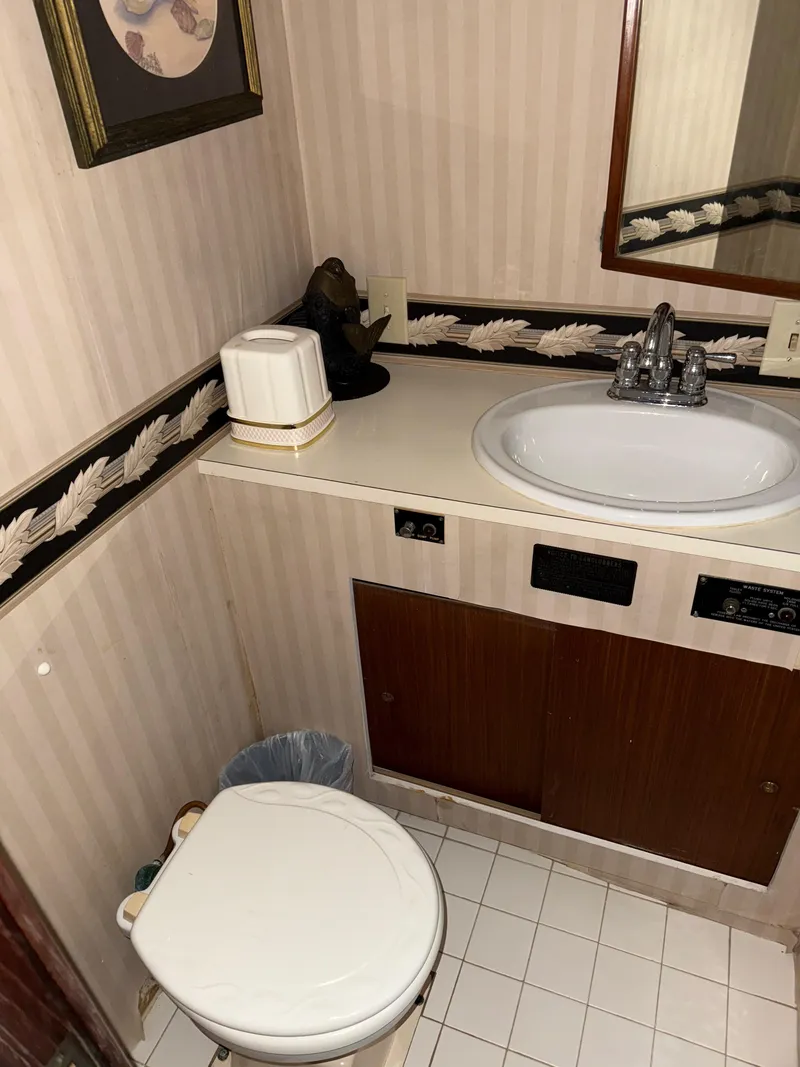 Slide: The Image of 1980 Hatteras 58MY yacht bathroom with sink, toilet, and decorative wallpaper. - 12