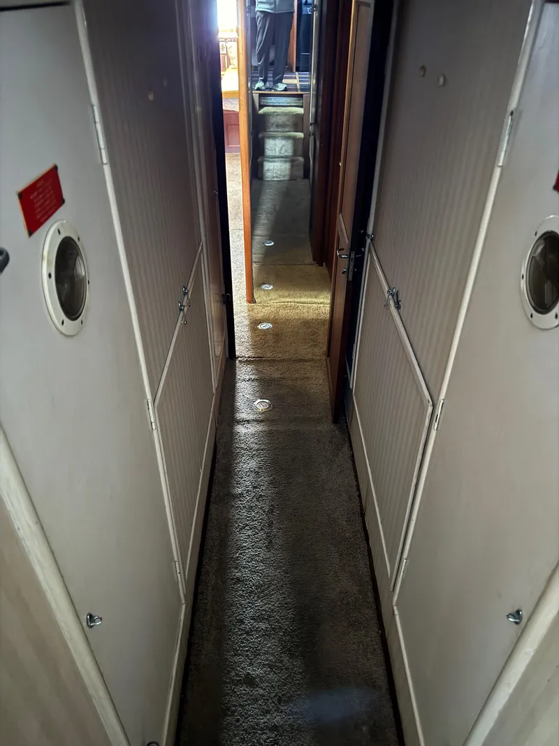 Slide: The Image of Narrow hallway inside a 1980 Hatteras 58MY yacht, featuring carpeted flooring and cabin doors. - 16