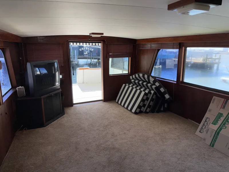 Slide: The Image of Interior of 1980 Hatteras 58MY yacht with carpet, TV, and striped cushions. - 7
