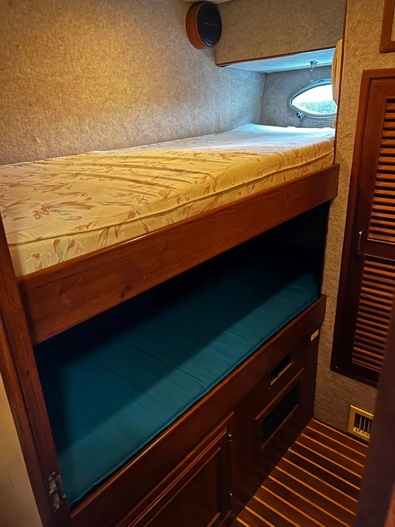 Slide: The Image of Bunk beds in a 1990 Nova 4500 RV, featuring wood paneling and cozy bedding. - 12