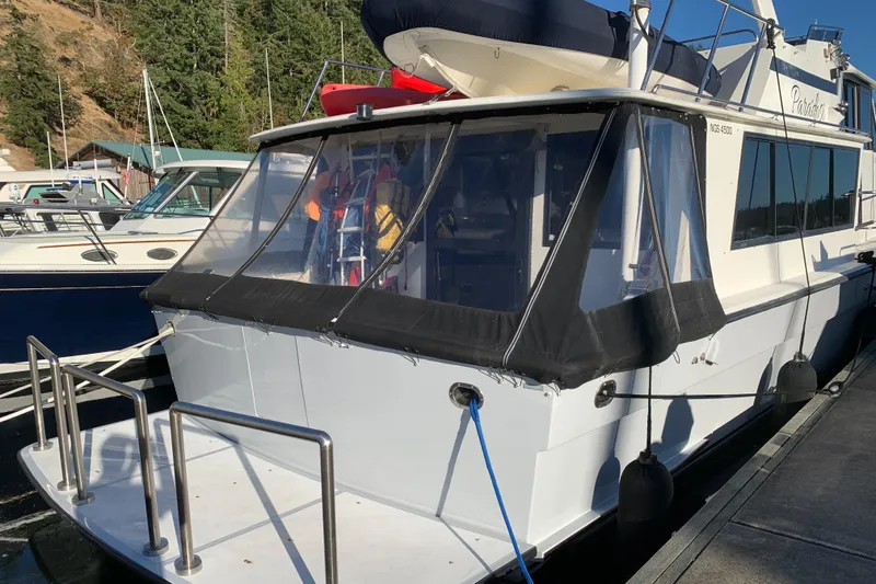 Slide: The Image of 1990 Nova 4500 boat docked, featuring a covered rear deck and visible marina background. - 28