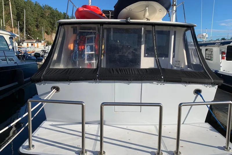 Slide: The Image of 1990 Nova 4500 boat docked, rear view with canopy and railing, clear sky background. - 29