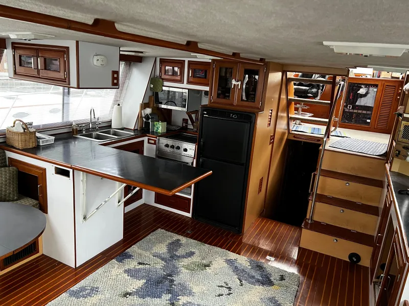 Slide: The Image of Interior of a 1990 Nova 4500 boat, featuring a kitchen and wooden flooring. - 9