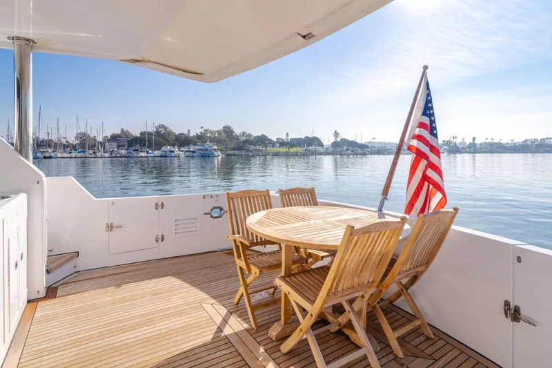 Slide: The Image of Ocean Alexander 64 Pilothouse 2003 yacht deck with wooden furniture and American flag. - 48