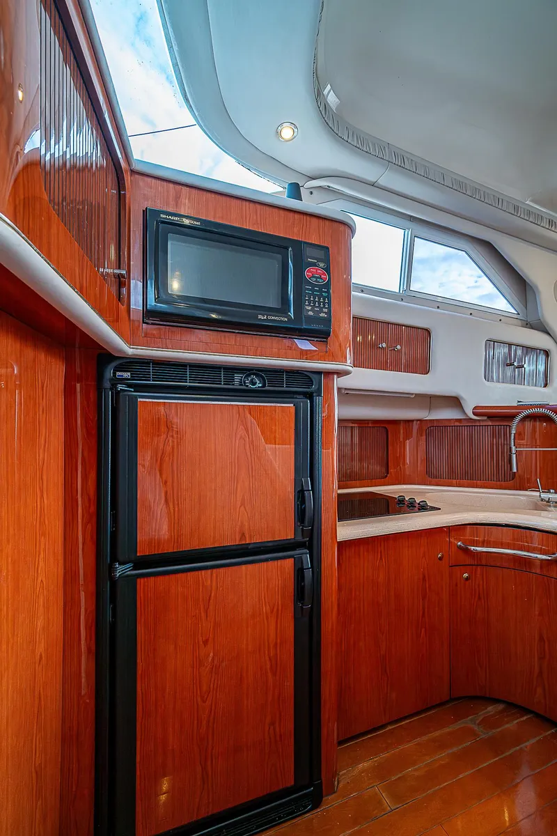 Slide: The Image of 2001 Sea Ray 400 Sedan Bridge kitchen with wood cabinetry and modern appliances. - 27