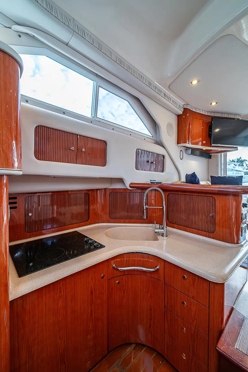 Slide: The Image of 2001 Sea Ray 400 Sedan Bridge kitchen with wood cabinetry and modern fixtures. - 28