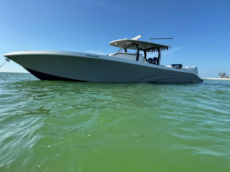 Slide: The Image of 2019 Fountain 43NX boat on calm green water under clear blue sky. - 0