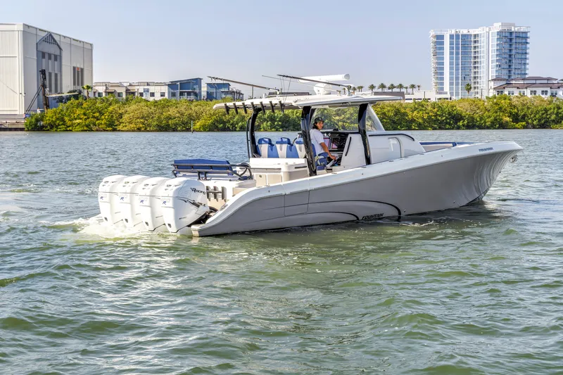 Slide: The Image of 2019 Fountain 43NX boat cruising on water with multiple engines, cityscape in background. - 12