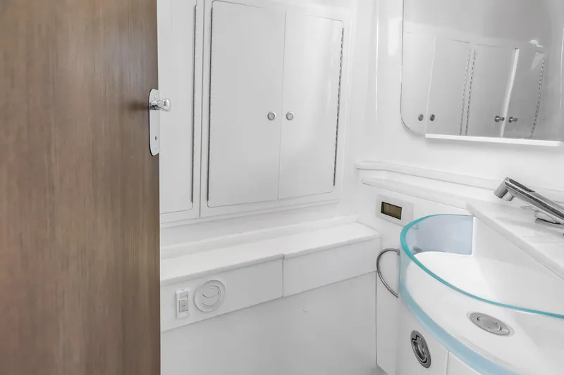 Slide: The Image of Modern bathroom interior on 2019 Fountain 43NX boat, featuring sleek white cabinetry and fixtures. - 25
