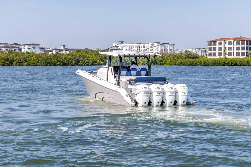 Slide: The Image of 2019 Fountain 43NX boat cruising on water with four engines, near modern buildings. - 5
