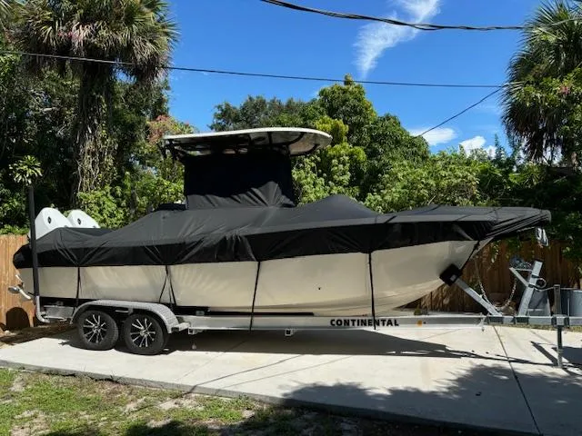 Slide: The Image of 2024 Sea Chaser 24 HFC boat covered on trailer, parked outdoors with lush greenery. - 18