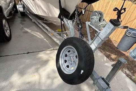 Slide: The Image of 2024 Sea Chaser 24 HFC boat trailer with spare tire on driveway. - 24