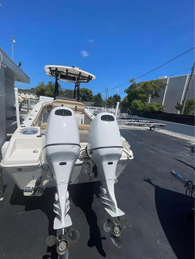 Slide: The Image of 2024 Sea Chaser 24 HFC boat with dual outboard motors, parked outdoors. - 4