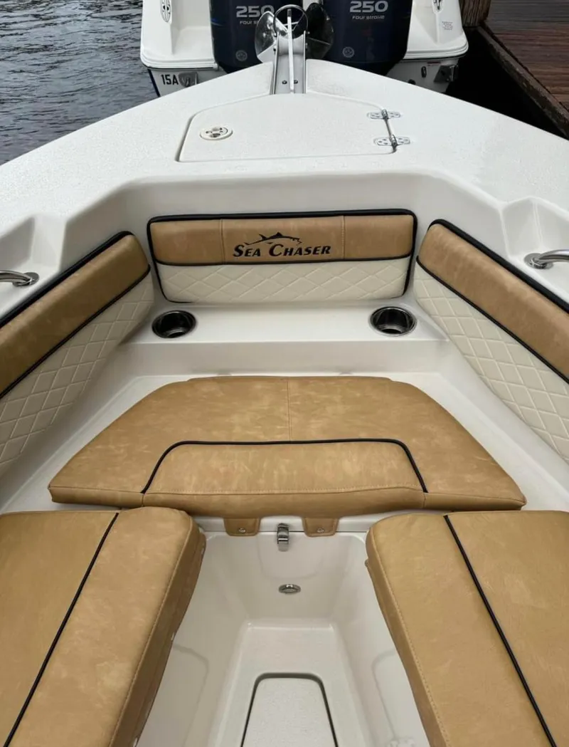 Slide: The Image of 2024 Sea Chaser 24 HFC boat interior with tan cushioned seating and logo. - 6