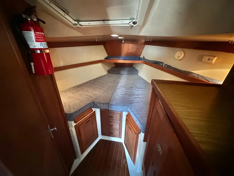 Slide: The Image of 1986 Catalina 36 yacht cabin interior with bed, wooden cabinets, and fire extinguisher. - 14
