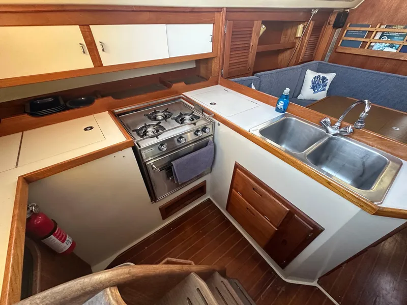 Slide: The Image of Interior of 1986 Catalina 36 sailboat kitchen with stove, sink, and wooden cabinetry. - 21