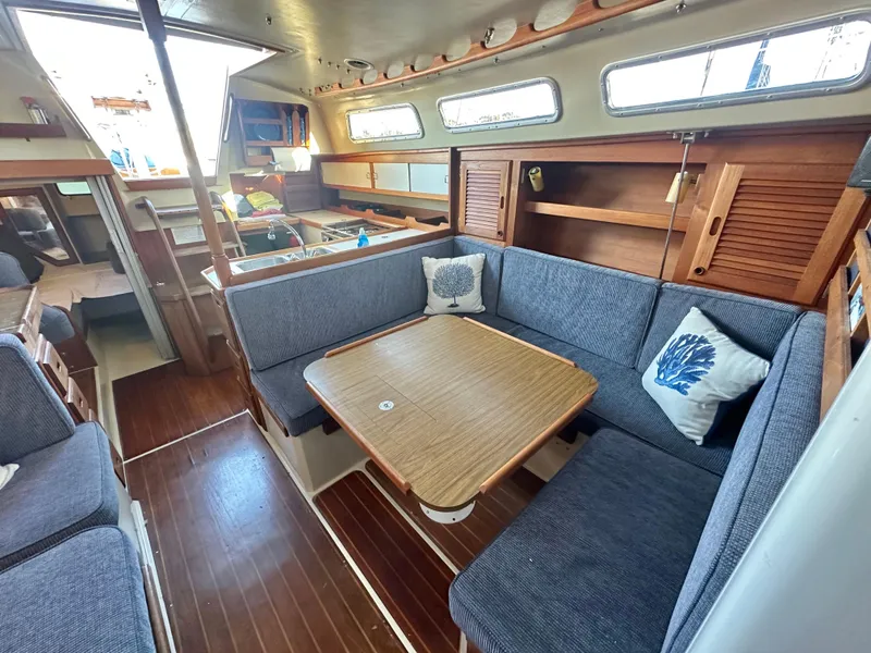 Slide: The Image of 1986 Catalina 36 yacht interior with cozy seating, wooden table, and nautical decor. - 23