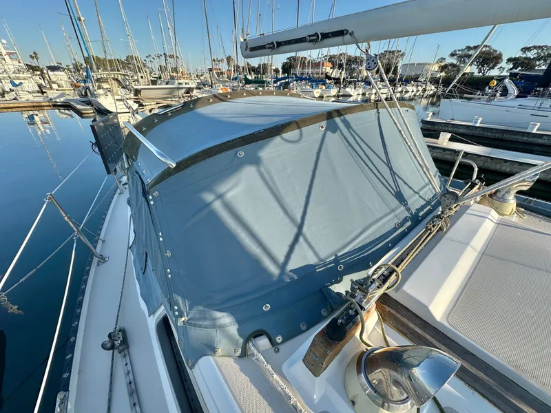 Slide: The Image of 1986 Catalina 36 sailboat docked in marina, featuring a covered cockpit area. - 6