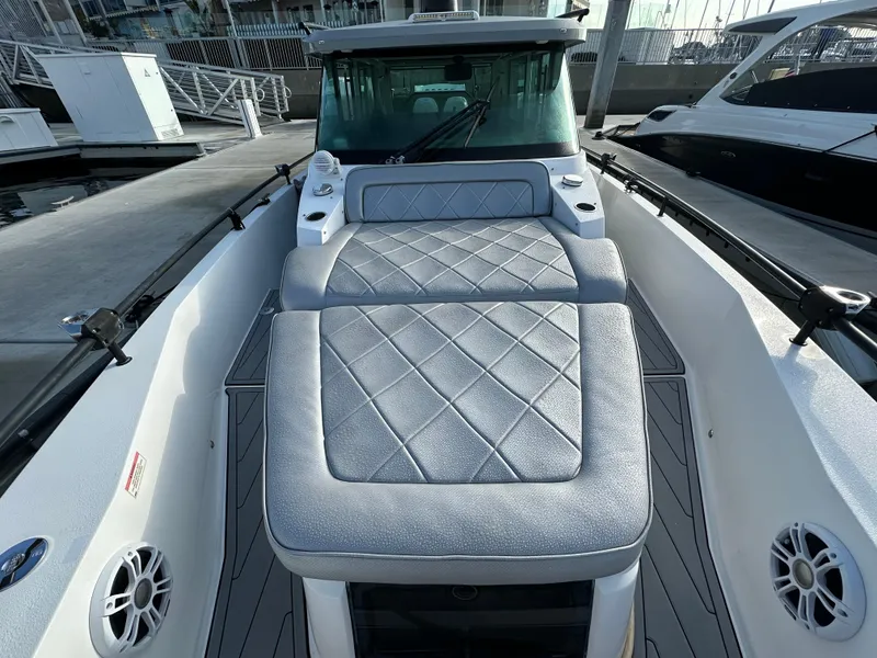 Slide: The Image of 2017 Axopar 37 boat with cushioned seating and sleek design at a marina. - 23