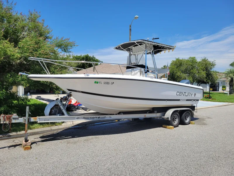 Slide: The Image of 2001 Century 2300 Center Console boat on trailer, parked on a sunny residential street. - 5
