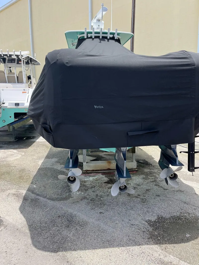 Slide: The Image of 2018 Yellowfin 36 boat with cover, showing triple propellers, parked outdoors. - 18