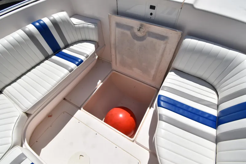 Slide: The Image of 2002 Intrepid 323 boat interior with white and blue seating, open storage compartment. - 14