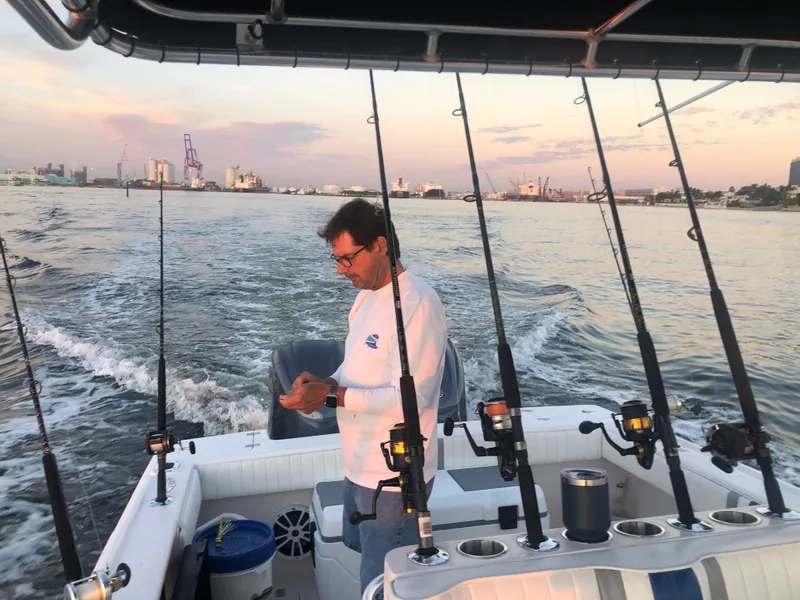 Slide: The Image of Man on 2002 Intrepid 323 boat with fishing rods, cityscape in background. - 16