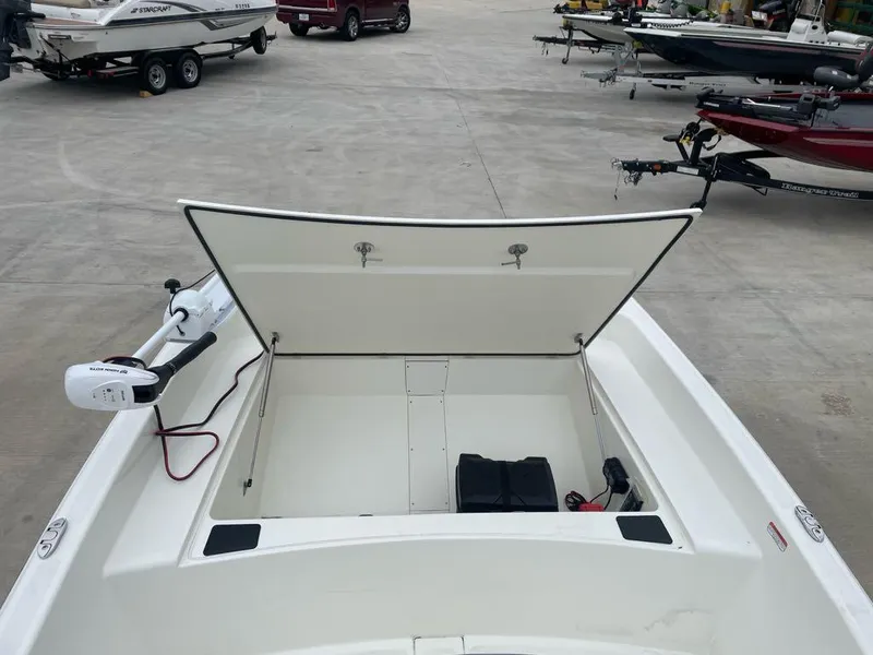 Slide: The Image of 2025 Mako Pro Skiff 17 CC with open storage compartment in a boatyard. - 5