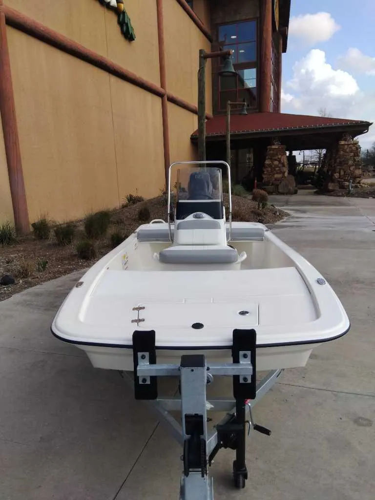Slide: The Image of 2025 Mako Pro Skiff 13 CC boat on trailer, parked outside a building. - 2