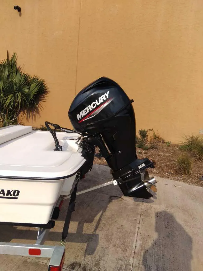 Slide: The Image of 2025 Mako Pro Skiff 13 CC with Mercury outboard motor, parked outdoors. - 3