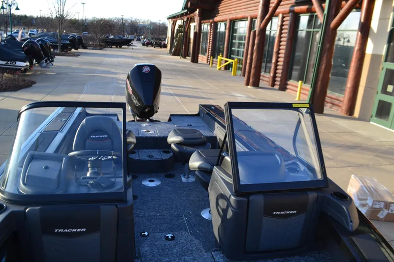 Slide: The Image of 2025 Tracker Targa V-19 WT boat with dual consoles, parked outside a log-style building. - 4