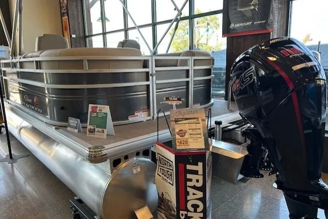 Slide: The Image of 2025 Sun Tracker Party Barge 22 DLX pontoon boat displayed indoors with Mercury outboard motor. - 2