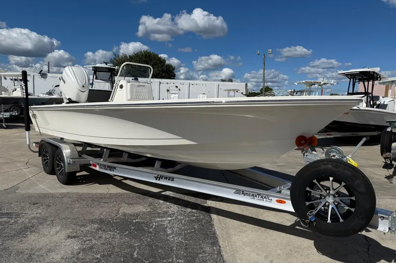 Slide: The Image of 2025 Hewes Redfisher 21 boat on trailer under a clear blue sky. - 0