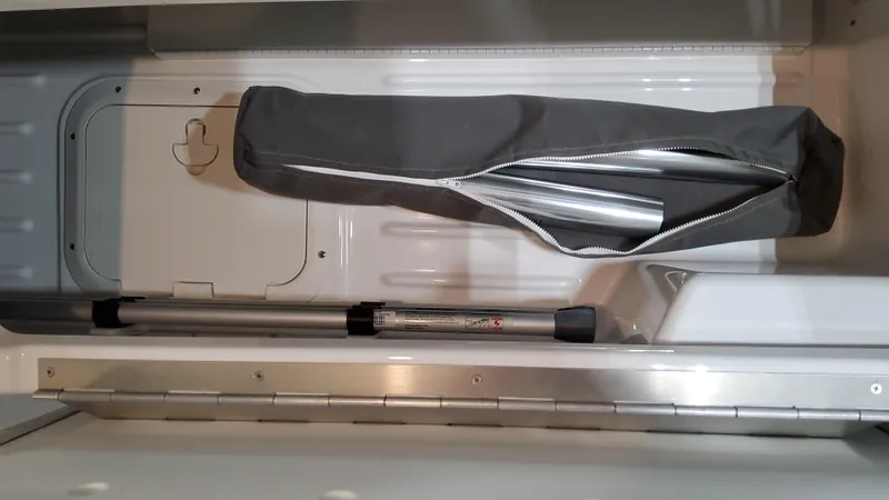 Slide: The Image of 2025 Formula 350 Crossover Bowrider I/O storage compartment with equipment bag and pole. - 20