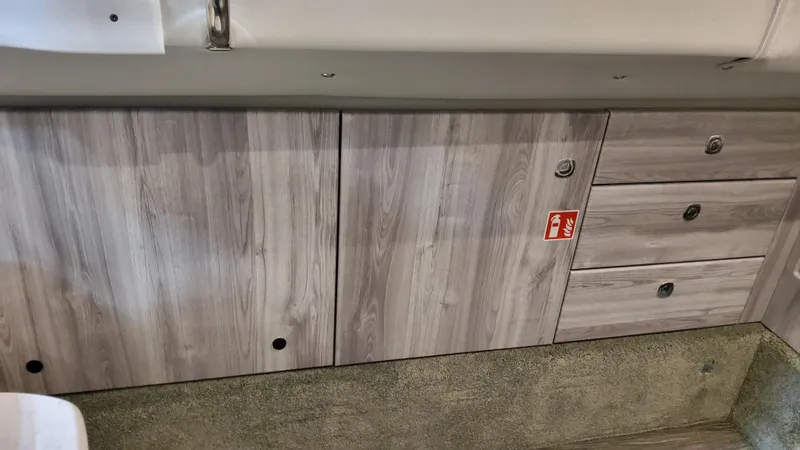 Slide: The Image of 2025 Formula 350 Crossover Bowrider I/O interior cabinetry with wood finish and storage drawers. - 48