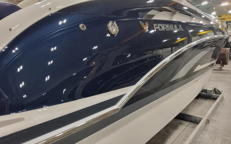Slide: The Image of 2025 Formula 310 Bowrider OB boat with sleek blue and white design in a showroom. - 2