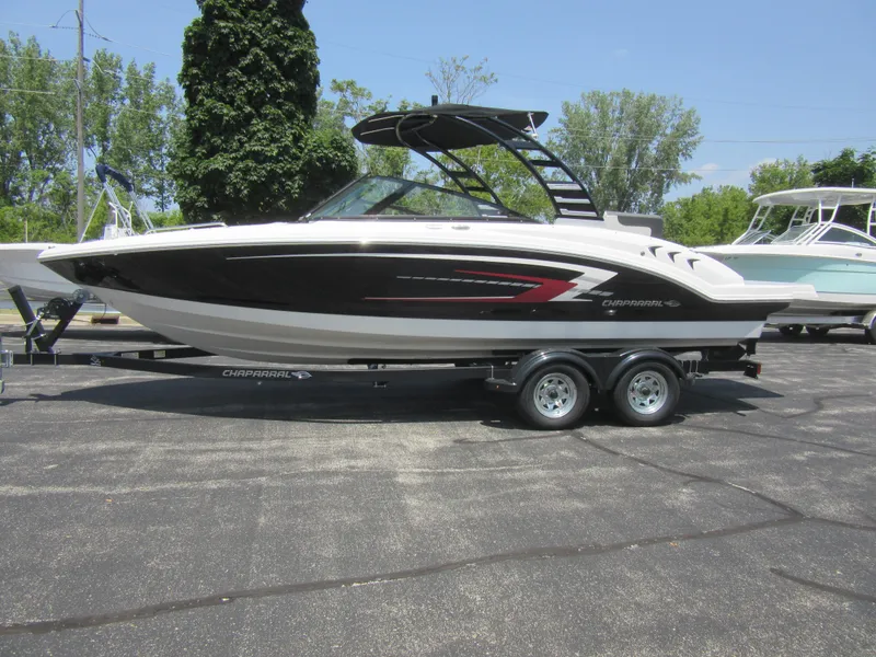 The Image of 2025 Chaparral 23 SSi boat on trailer, sleek black and white design, parked outdoors. - 1