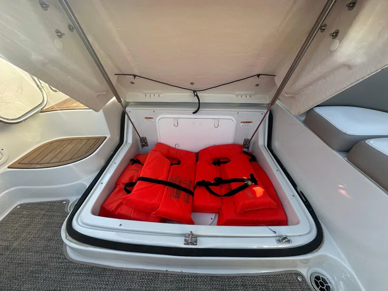 Slide: The Image of Open storage compartment with red life jackets in a 2019 Crownline Eclipse E235 XS boat. - 22