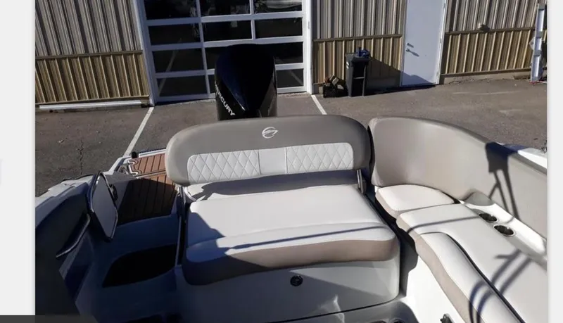 Slide: The Image of 2019 Crownline Eclipse E235 XS boat interior with seating and motor, parked outdoors. - 5