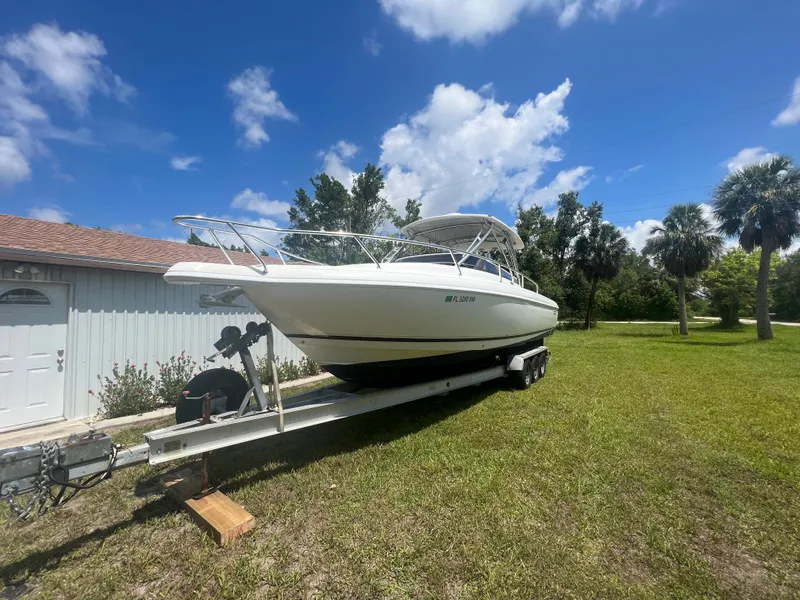 Slide: The Image of 2009 Intrepid 310 WA boat on trailer, parked on grass under a clear blue sky. - 28