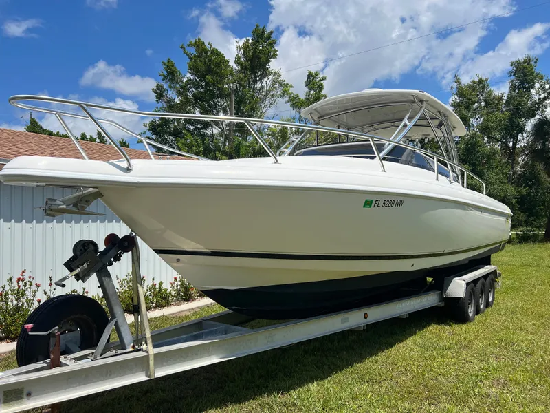 Slide: The Image of 2009 Intrepid 310 WA boat on trailer, parked on grass under a clear blue sky. - 29