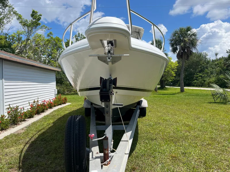 Slide: The Image of 2009 Intrepid 310 WA boat on trailer, parked on grass, with trees and a house nearby. - 30