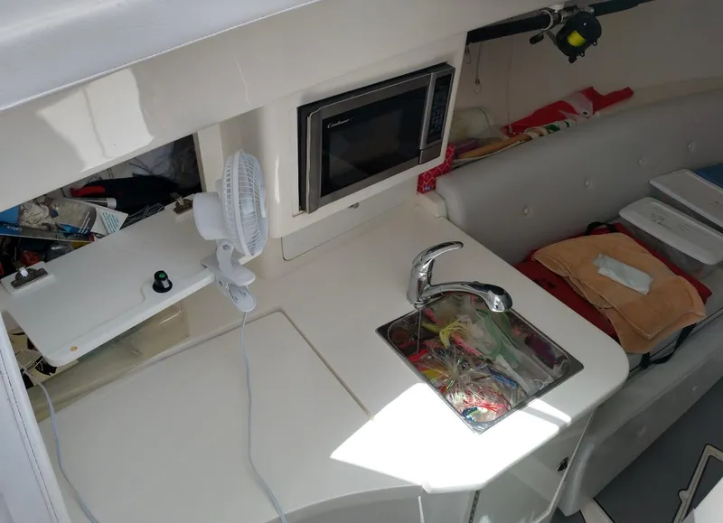 Slide: The Image of 2009 Intrepid 310 WA boat interior with sink, microwave, and seating area. - 8