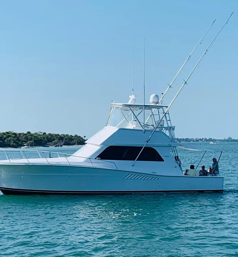 Slide: The Image of 1998 Viking 43 Convertible yacht on calm waters, clear sky, fishing rods visible. - 25