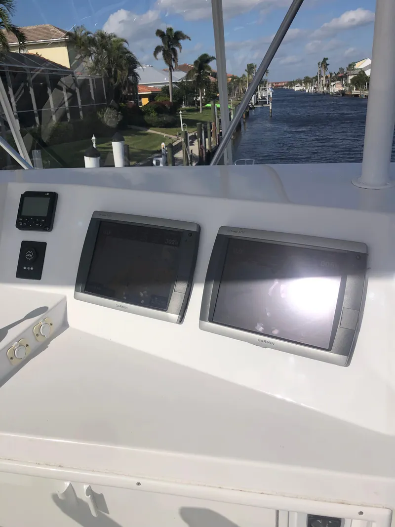 Slide: The Image of 1998 Viking 43 Convertible yacht dashboard with dual navigation screens, docked by a scenic canal. - 26